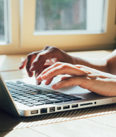 Two hands typing on a laptop.